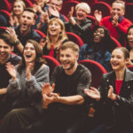 Group of excited people clapping hands in the theater.